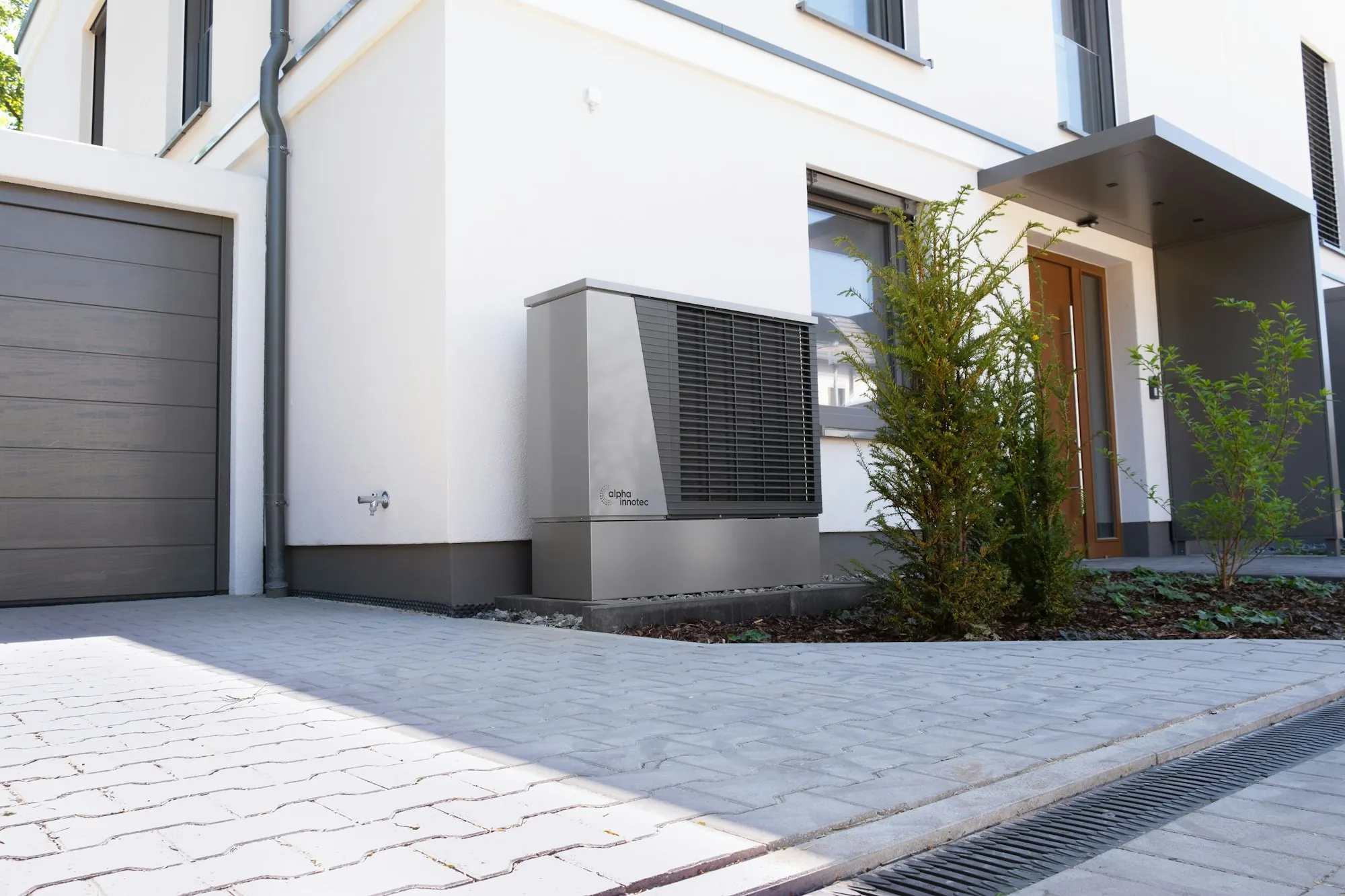 Heat pump unit beside a modern home entrance and driveway