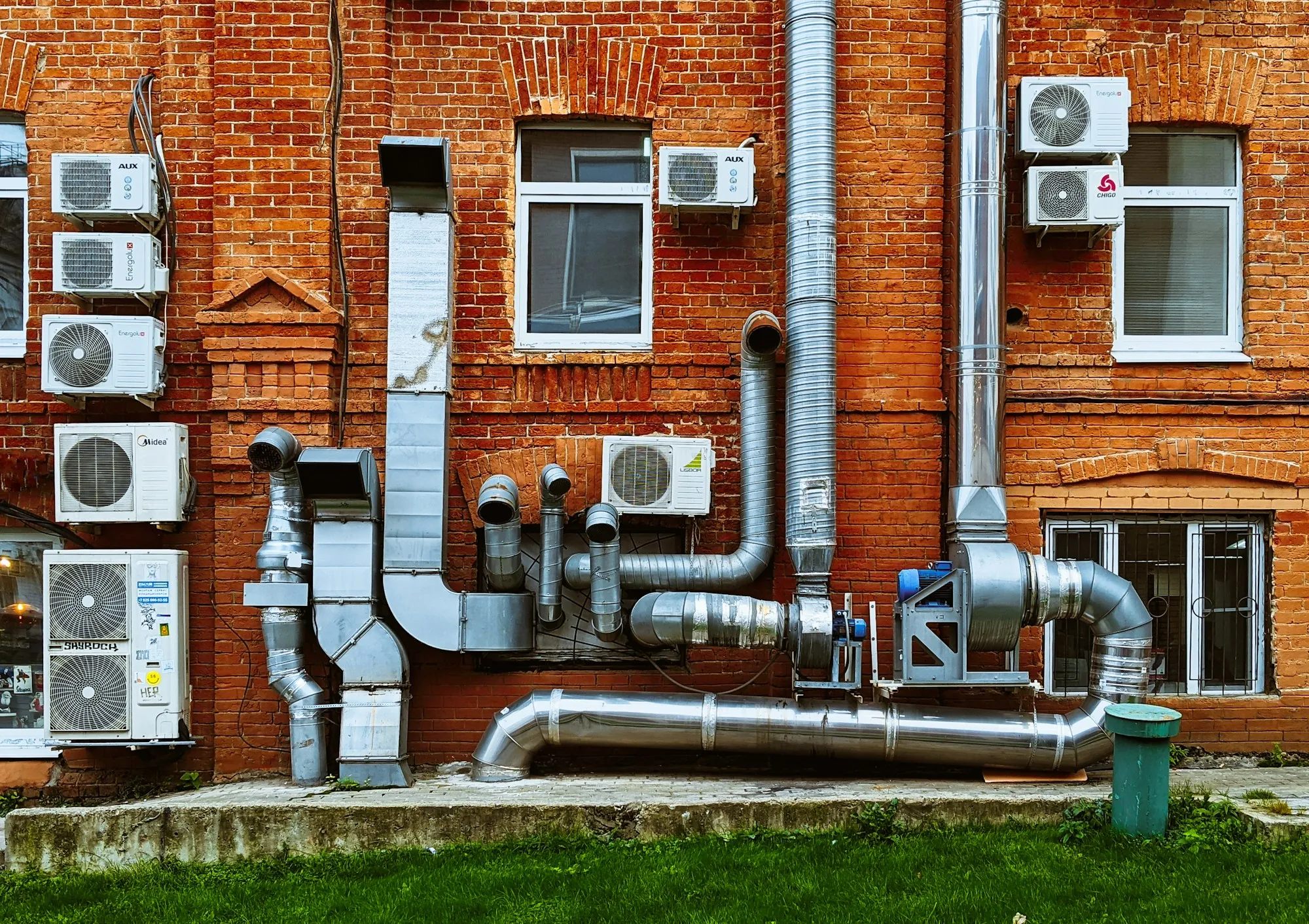 Brick building wall lined with ducts and AC units