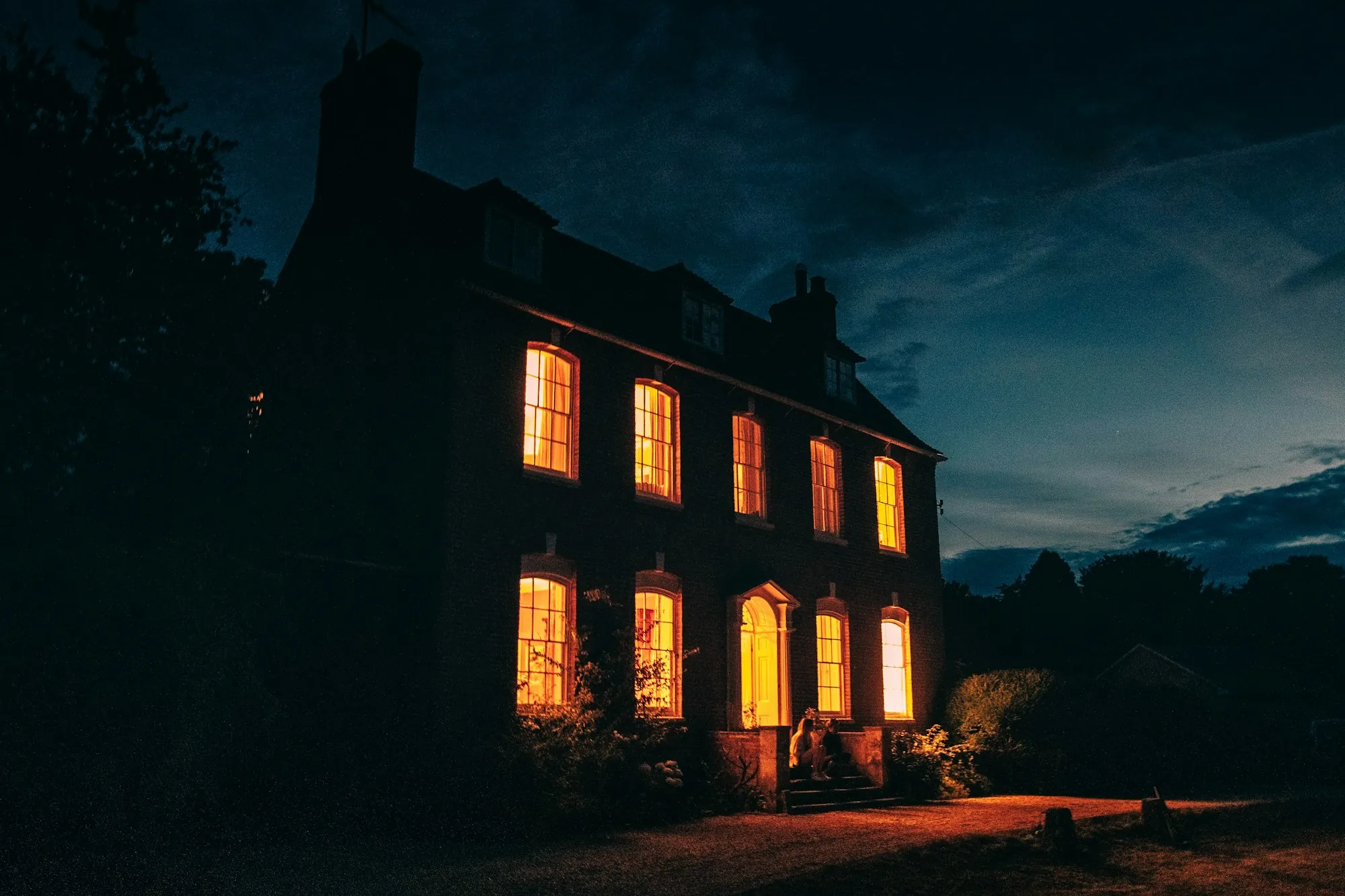 Large house with glowing windows under a night sky
